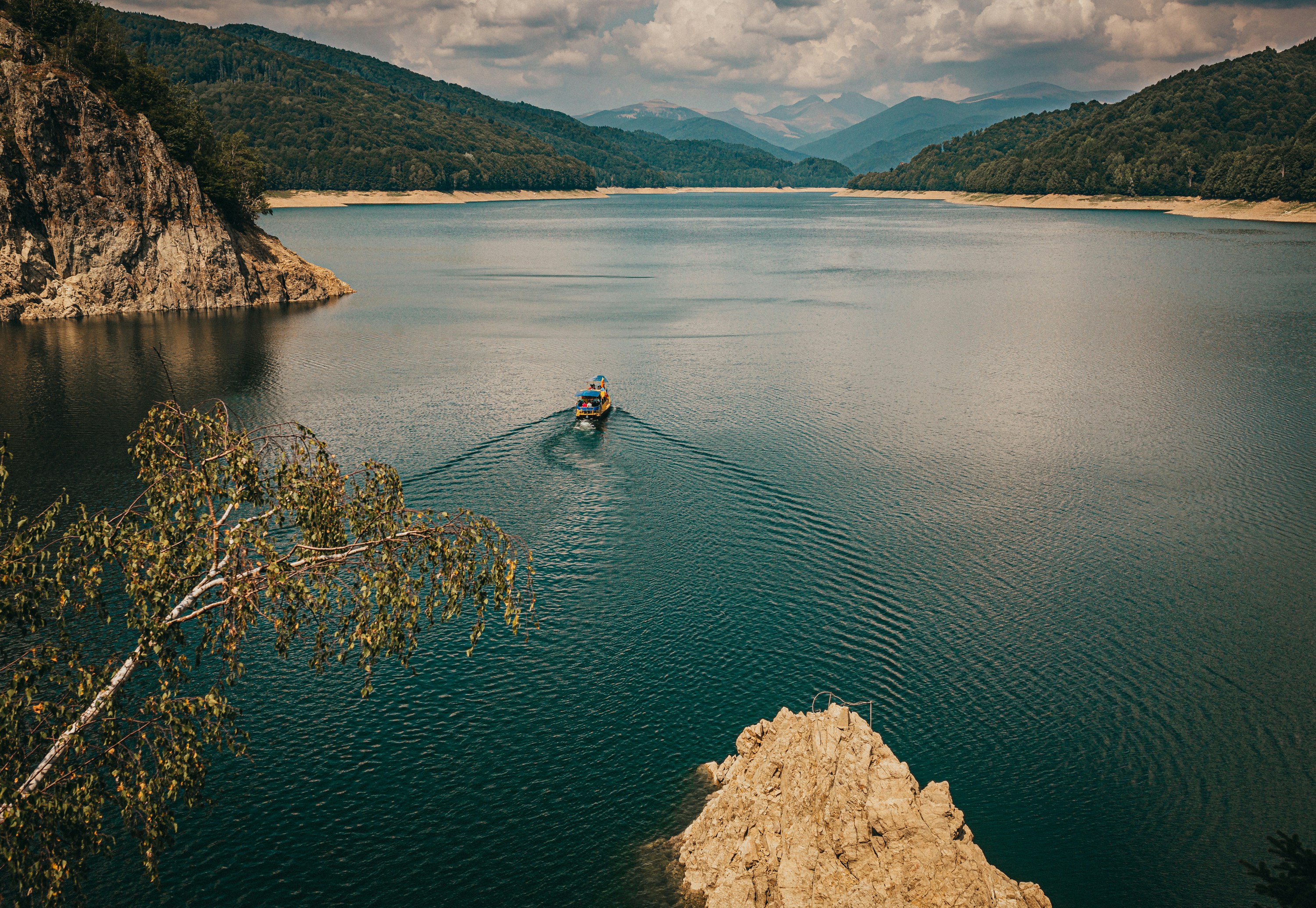 Person in blue jacket and blue jeans riding on blue kayak on lake
