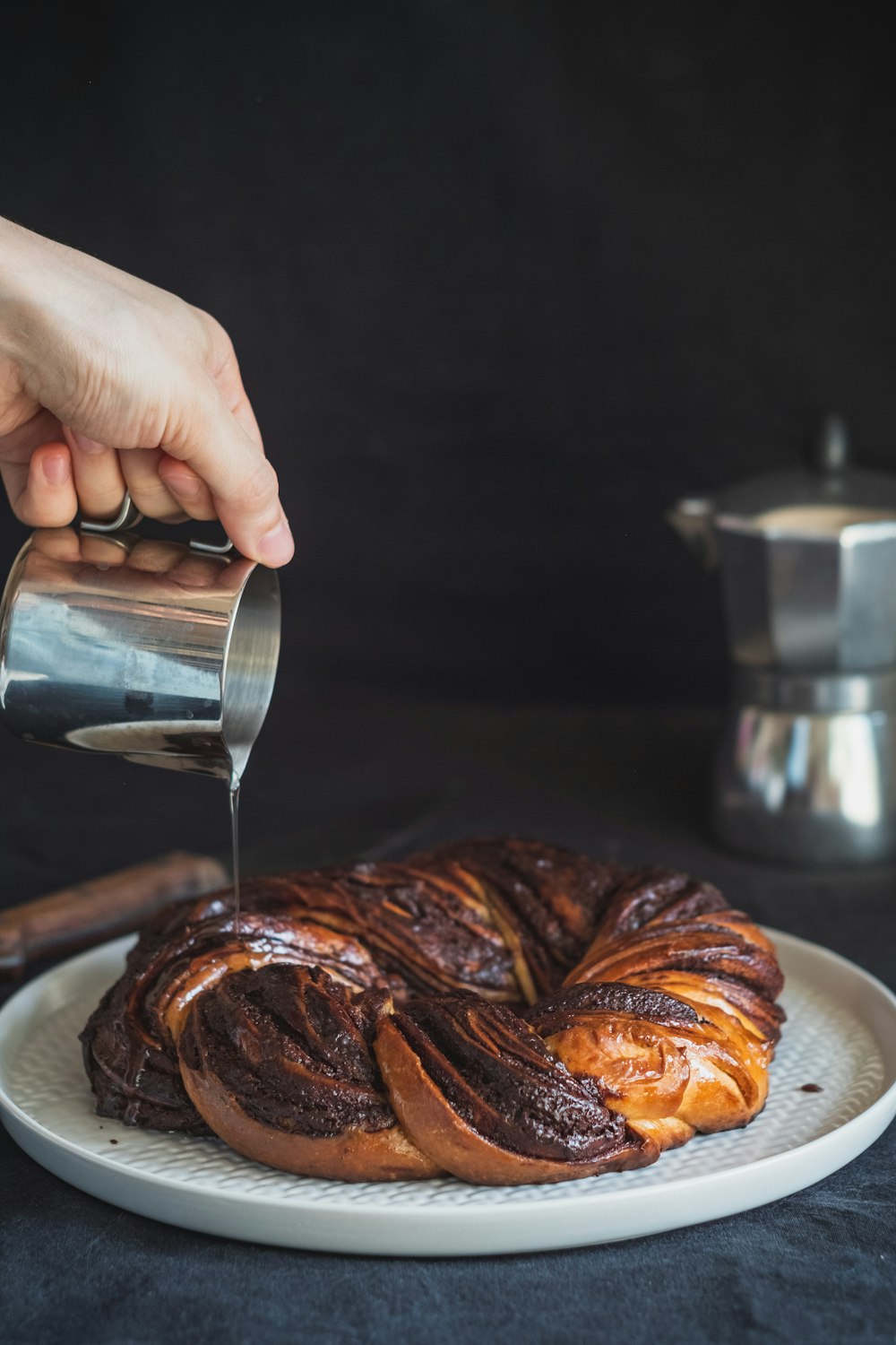 person pouring coffee on white ceramic plate