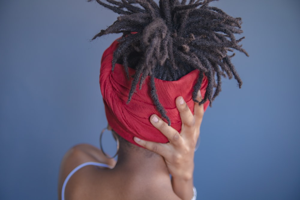 woman in white tank top holding red feather