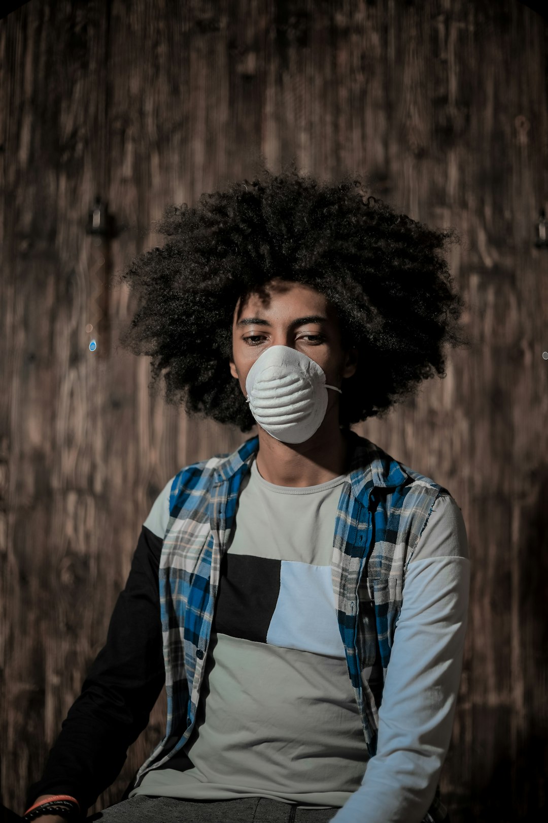 woman in blue and white plaid dress shirt wearing white mask