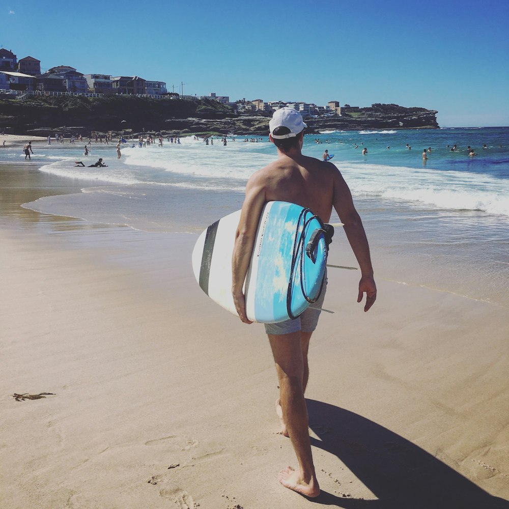 woman in blue and white bikini walking on beach during daytime