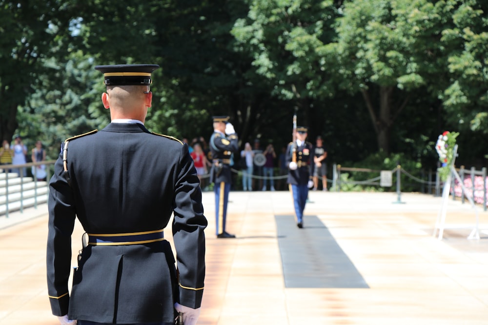 Homme en uniforme noir debout sur un sol en béton gris pendant la journée