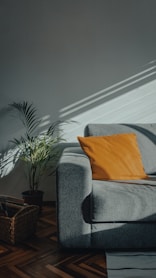 orange throw pillow on gray couch