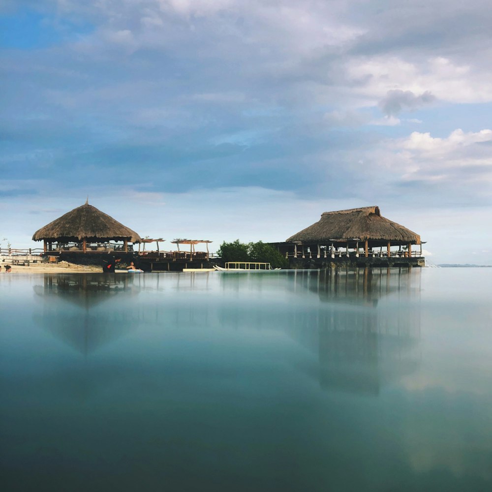 brown wooden house on water under blue sky during daytime