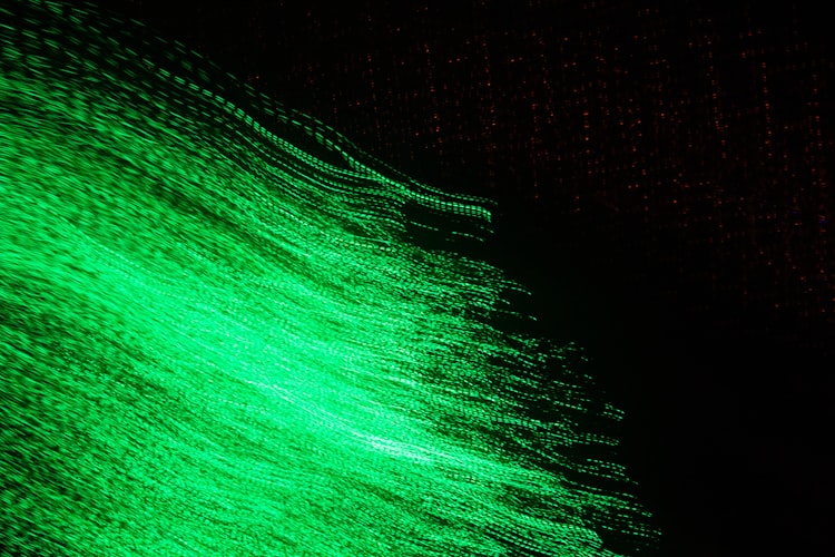 Abstract image of luminous bright green strands waving against a black background.