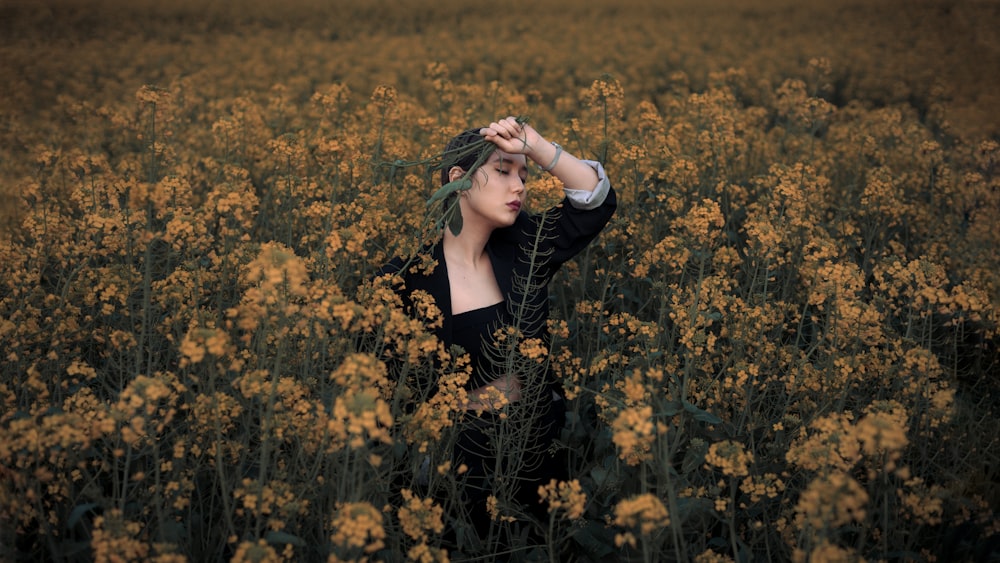 woman in black and white stripe long sleeve shirt standing on yellow flower field during daytime