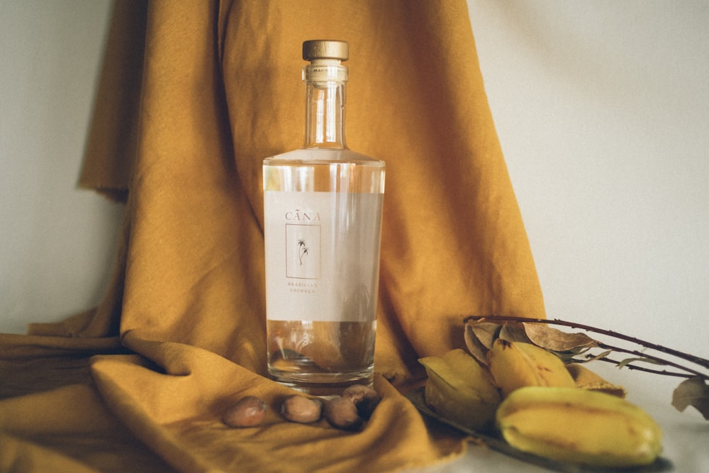 clear glass bottle on yellow textile