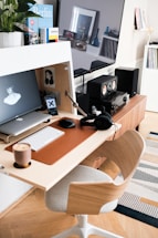 A cozy workspace with a laptop, headphones, and a compact speaker on the desk.