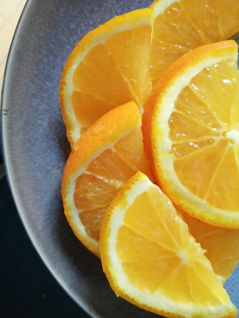 sliced orange fruit on gray round plate