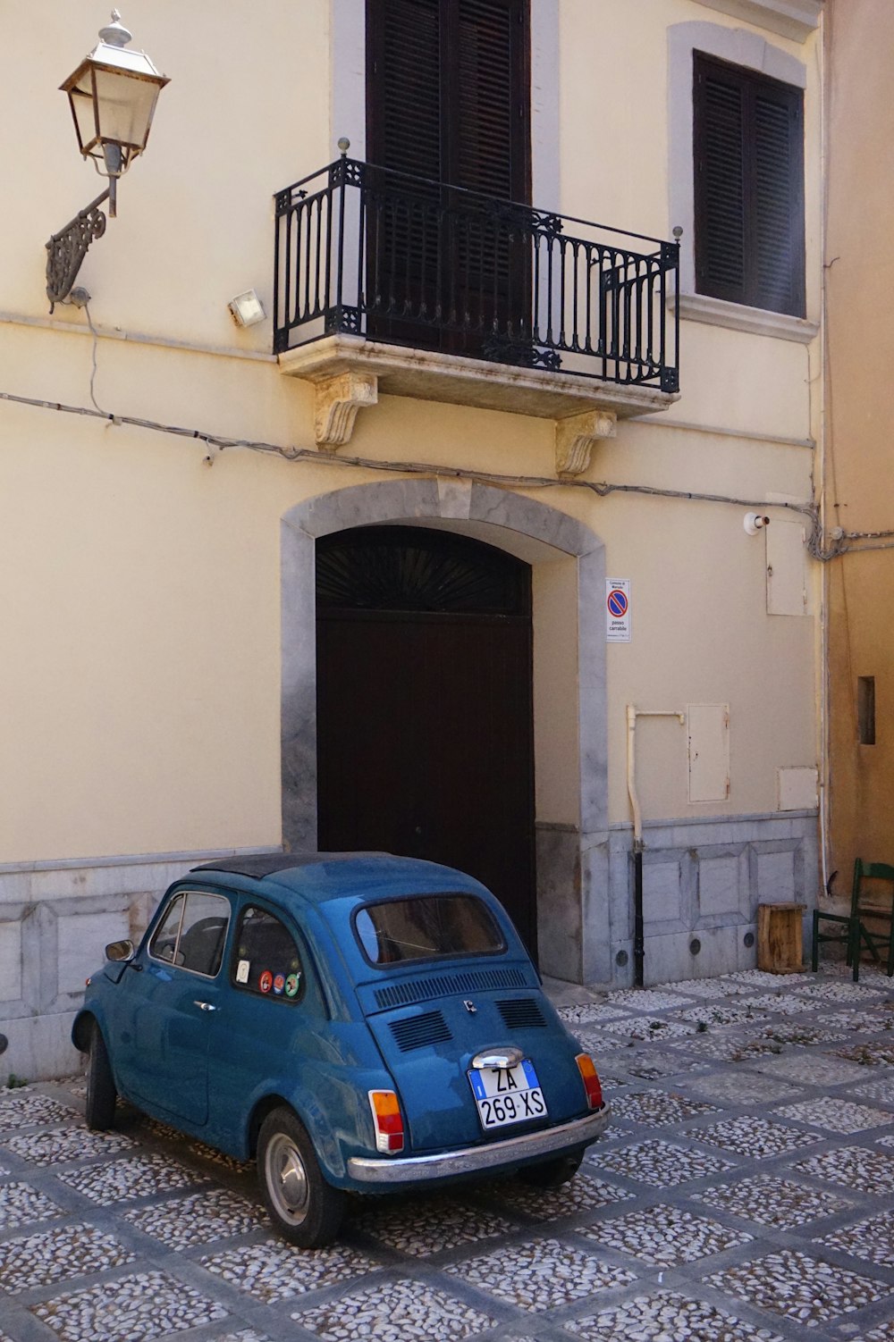 blue sedan parked beside white concrete building during daytime