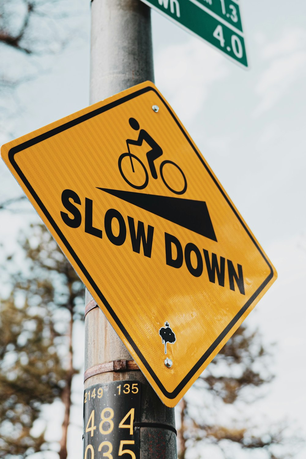 a yellow slow down sign on a pole