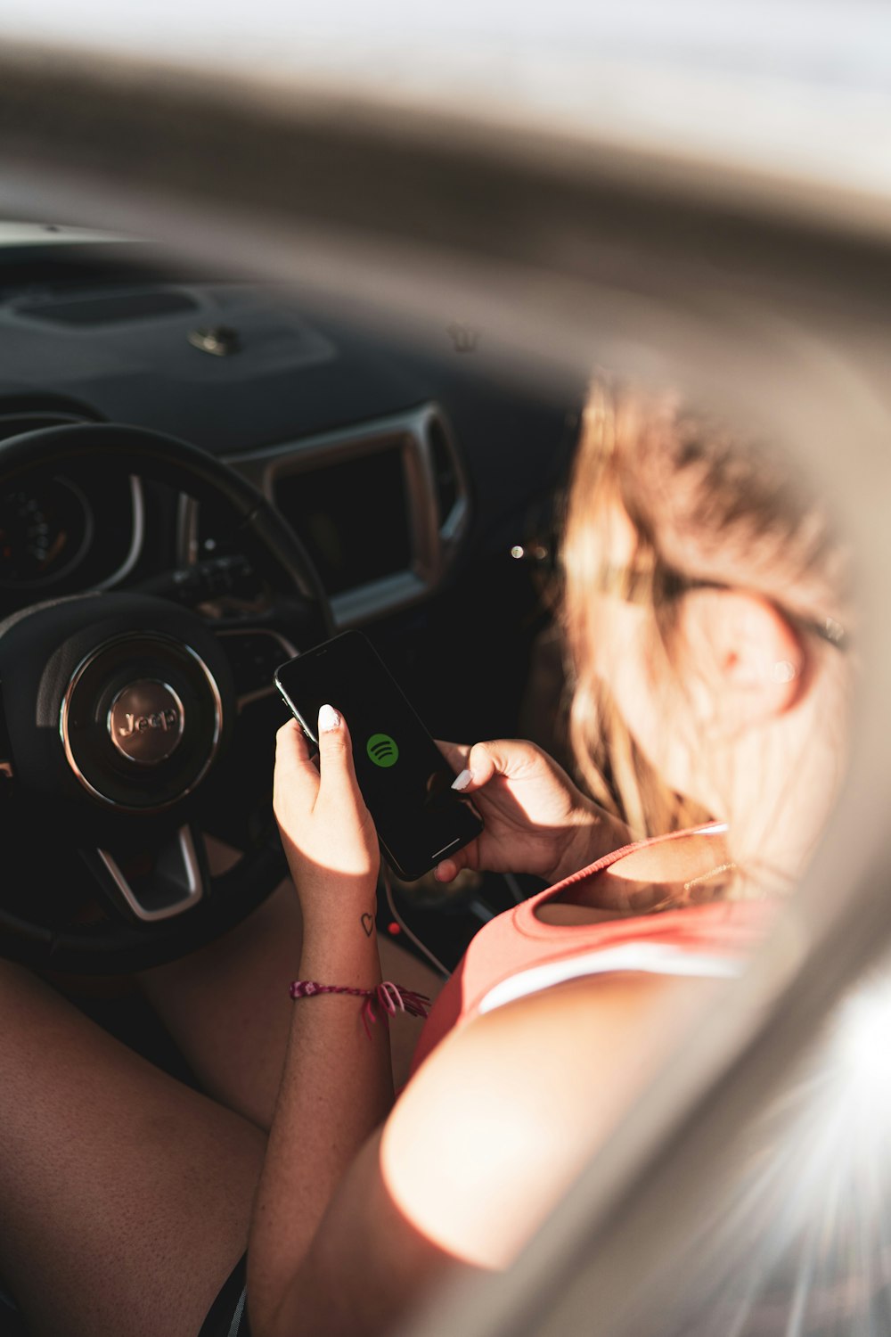 woman in pink tank top holding black smartphone