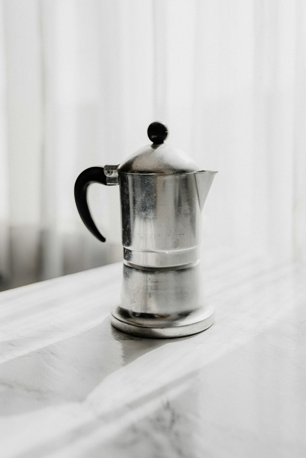 stainless steel teapot on white textile