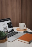 macbook pro beside white ceramic mug on brown wooden table