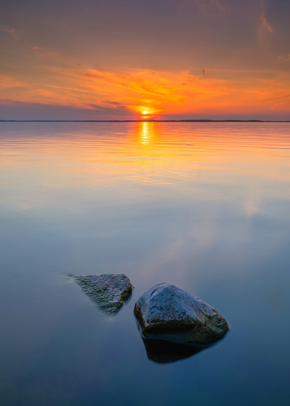 roche grise sur le plan d’eau au coucher du soleil