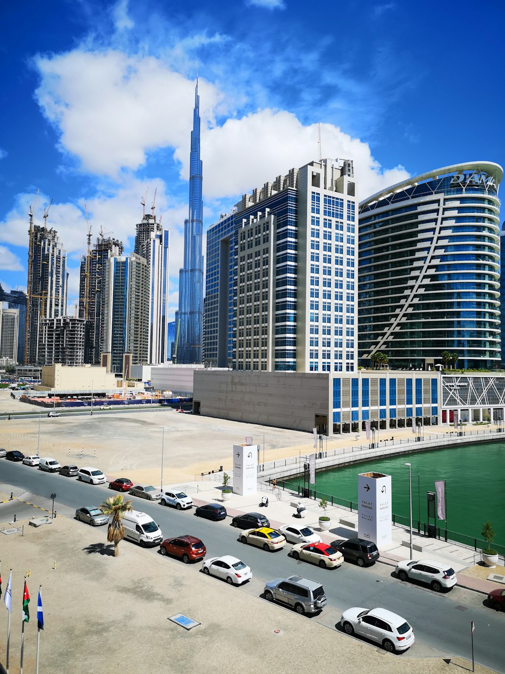 cars parked on parking lot near high rise buildings during daytime