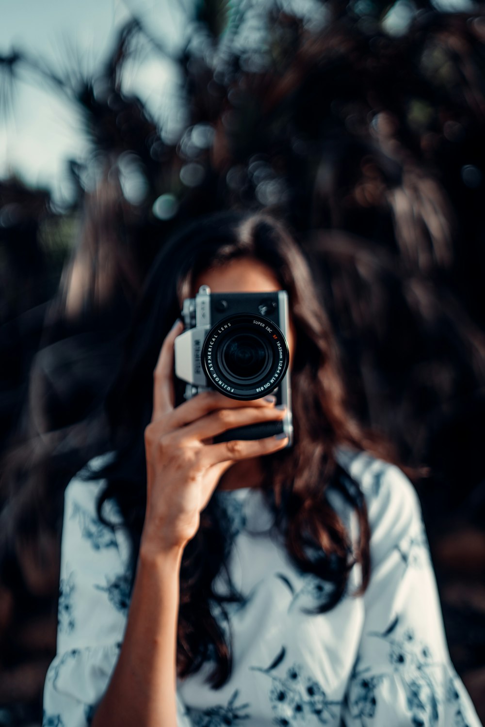 Femme en chemise blanche tenant un appareil photo noir et argenté