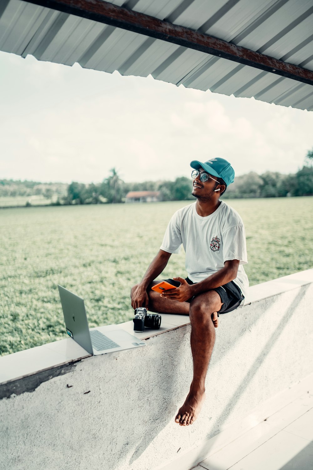 man in white crew neck t-shirt and blue cap sitting on white concrete bench