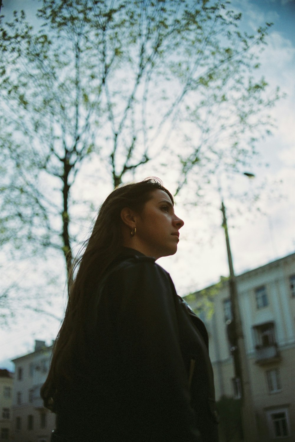 woman in black coat standing under white tree during daytime