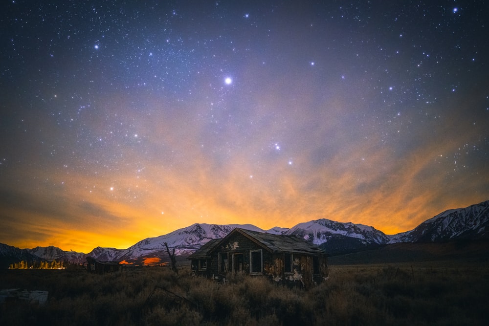 brown wooden house near snow covered mountain during night time