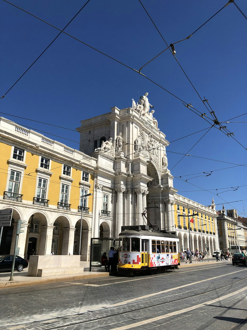 yellow and white tram on road near beige concrete building during daytime