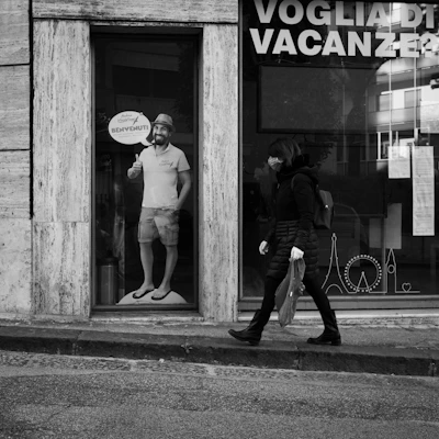 grayscale photo of man and woman walking on sidewalk