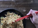 Hand picking up freshly cooked soba noodles with chopsticks