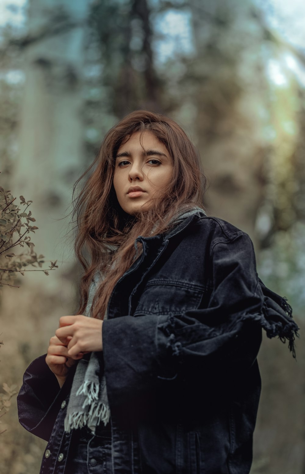 woman in black jacket standing near trees during daytime