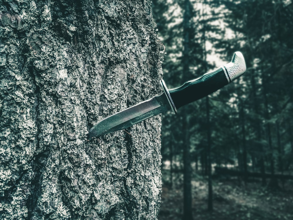 cuchillo negro y plateado en árbol marrón