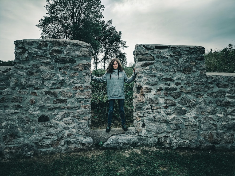 woman in gray jacket standing in front of gray concrete wall