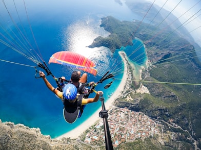 man in blue and black jacket riding on blue and white parachute