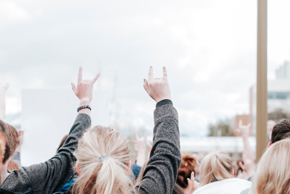 people raising their hands during daytime