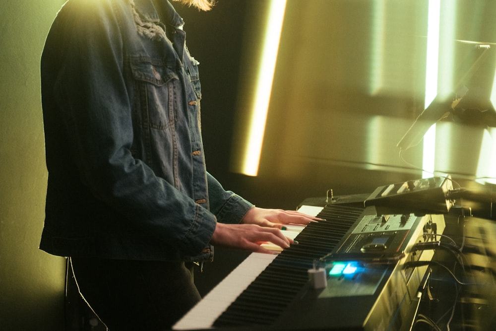 uomo in giacca di jeans blu che suona il pianoforte