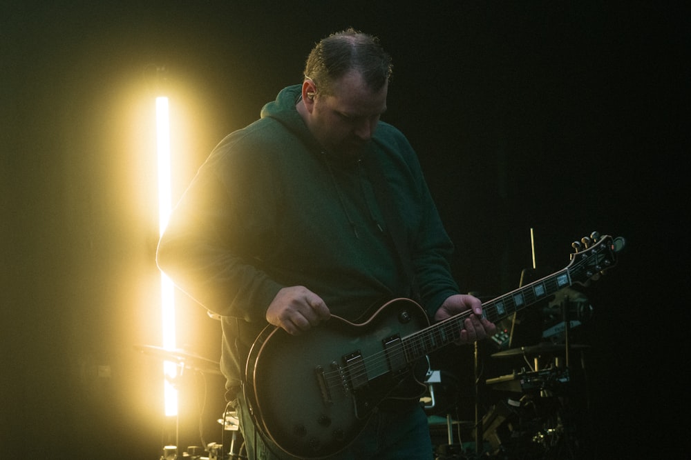 man in black dress shirt playing electric guitar