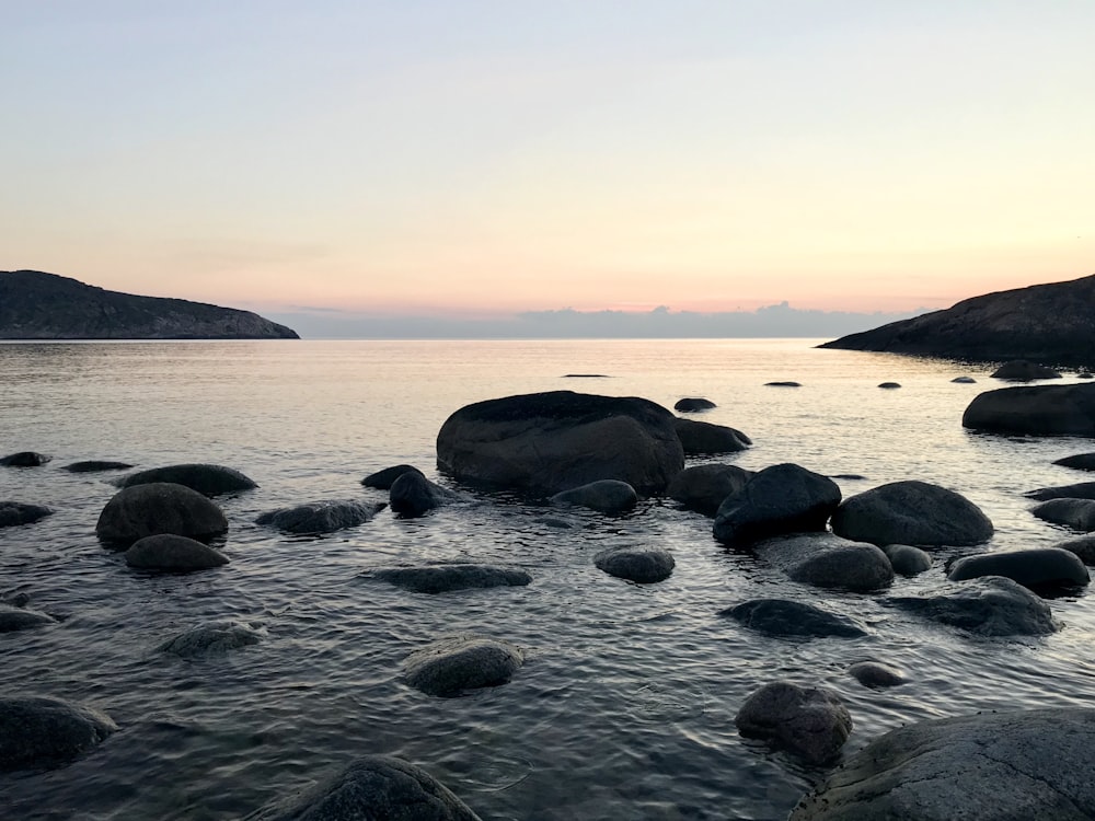 black rocks on body of water during daytime