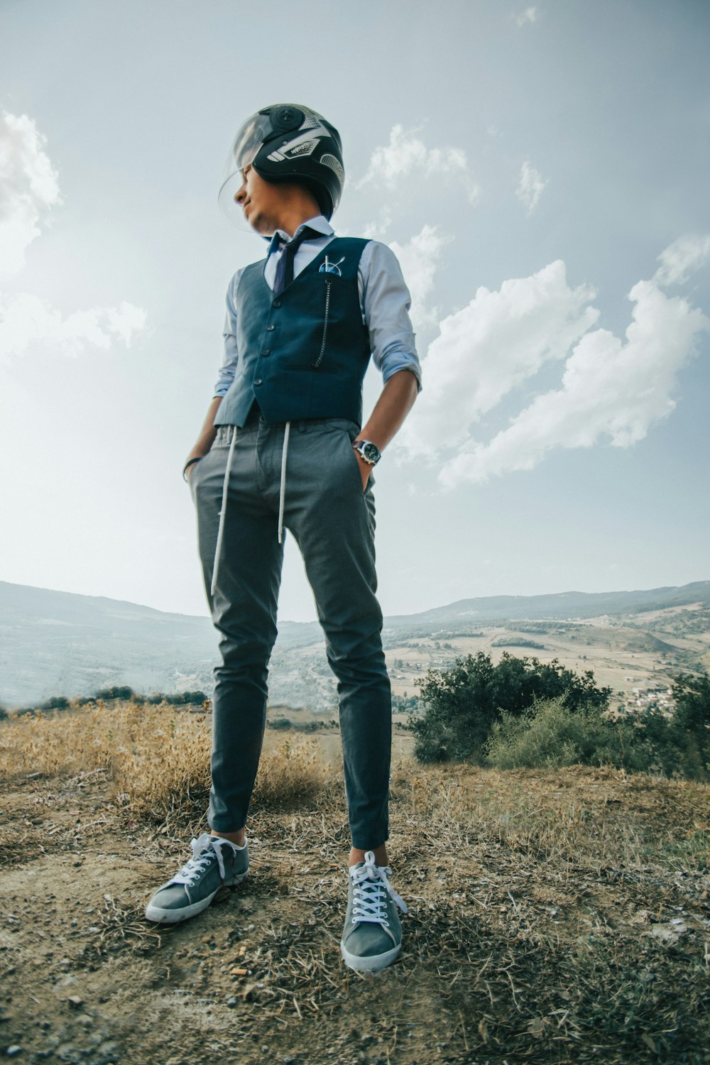 man in blue button up shirt and blue denim jeans standing on brown grass field during