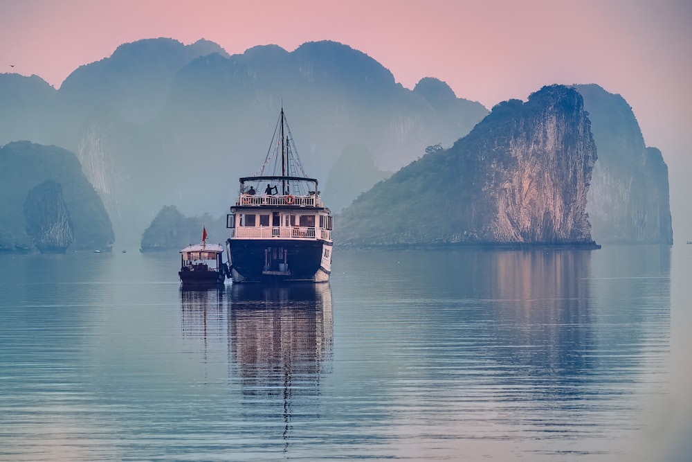 white and black boat on water near mountain during daytime