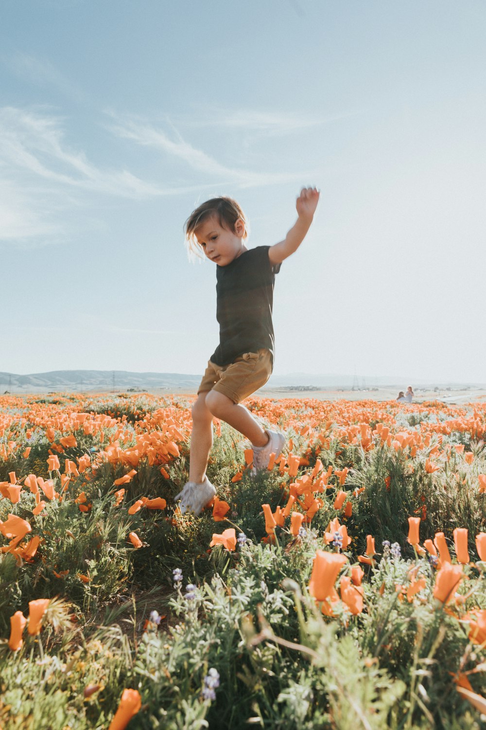 girl in black tank top running on flower field during daytime