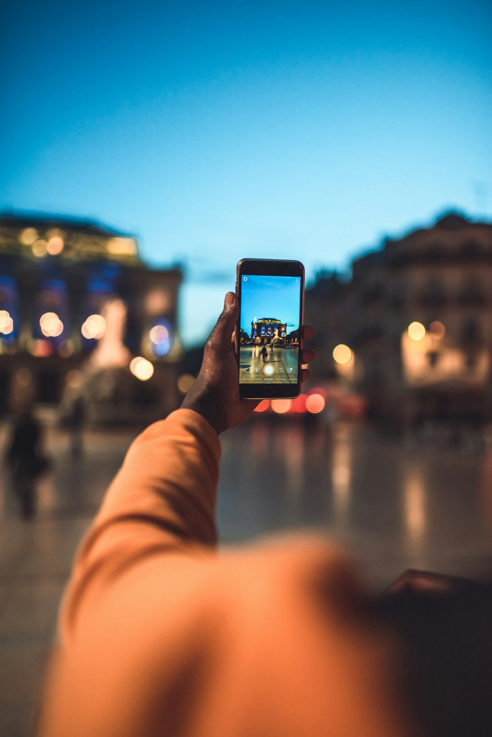 Persona que sostiene un teléfono inteligente negro tomando una foto de la ciudad durante la noche