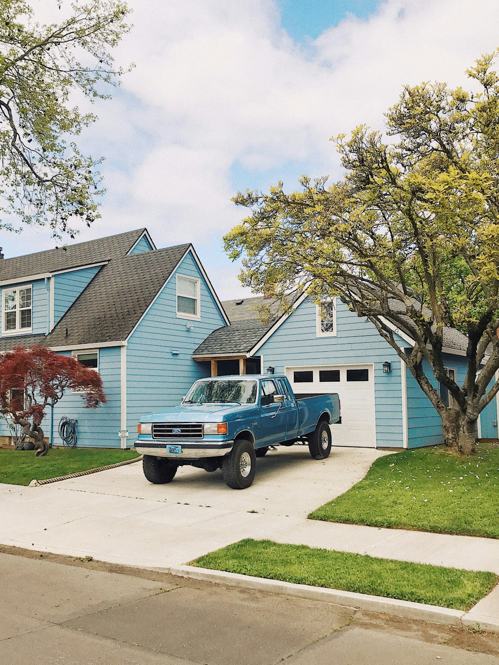 blue chevrolet crew cab pickup truck parked beside green tree during daytime