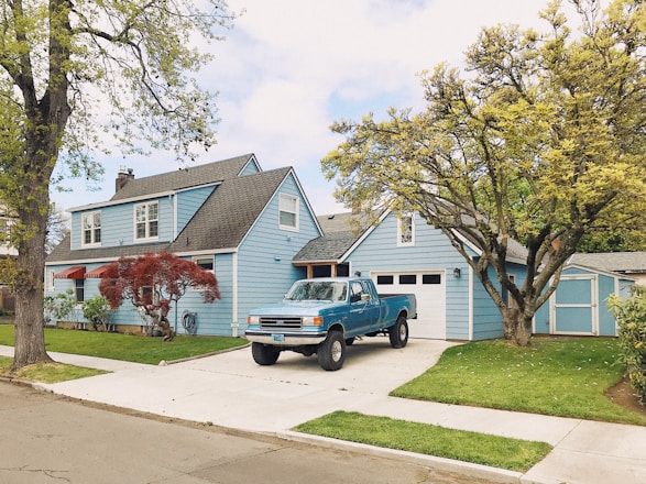 A cozy home with a car parked outside under a clear blue sky, symbolizing protection.