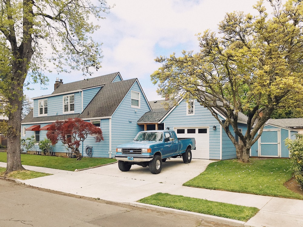 blue and white single cab pickup truck parked near green tree during daytime