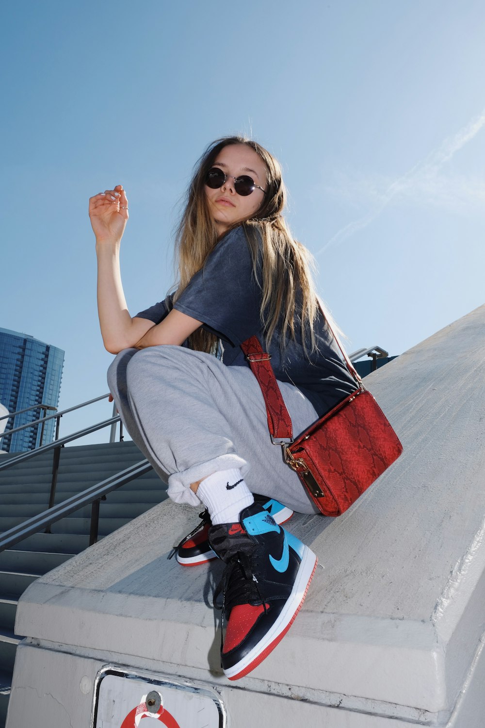 woman in gray t-shirt and gray pants sitting on gray concrete bench during daytime