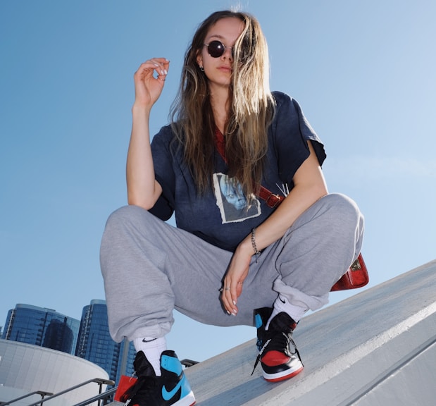 woman in black t-shirt and gray pants sitting on white metal railings during daytime