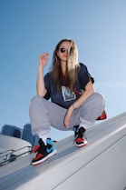 woman in black t-shirt and gray pants sitting on white metal railings during daytime
