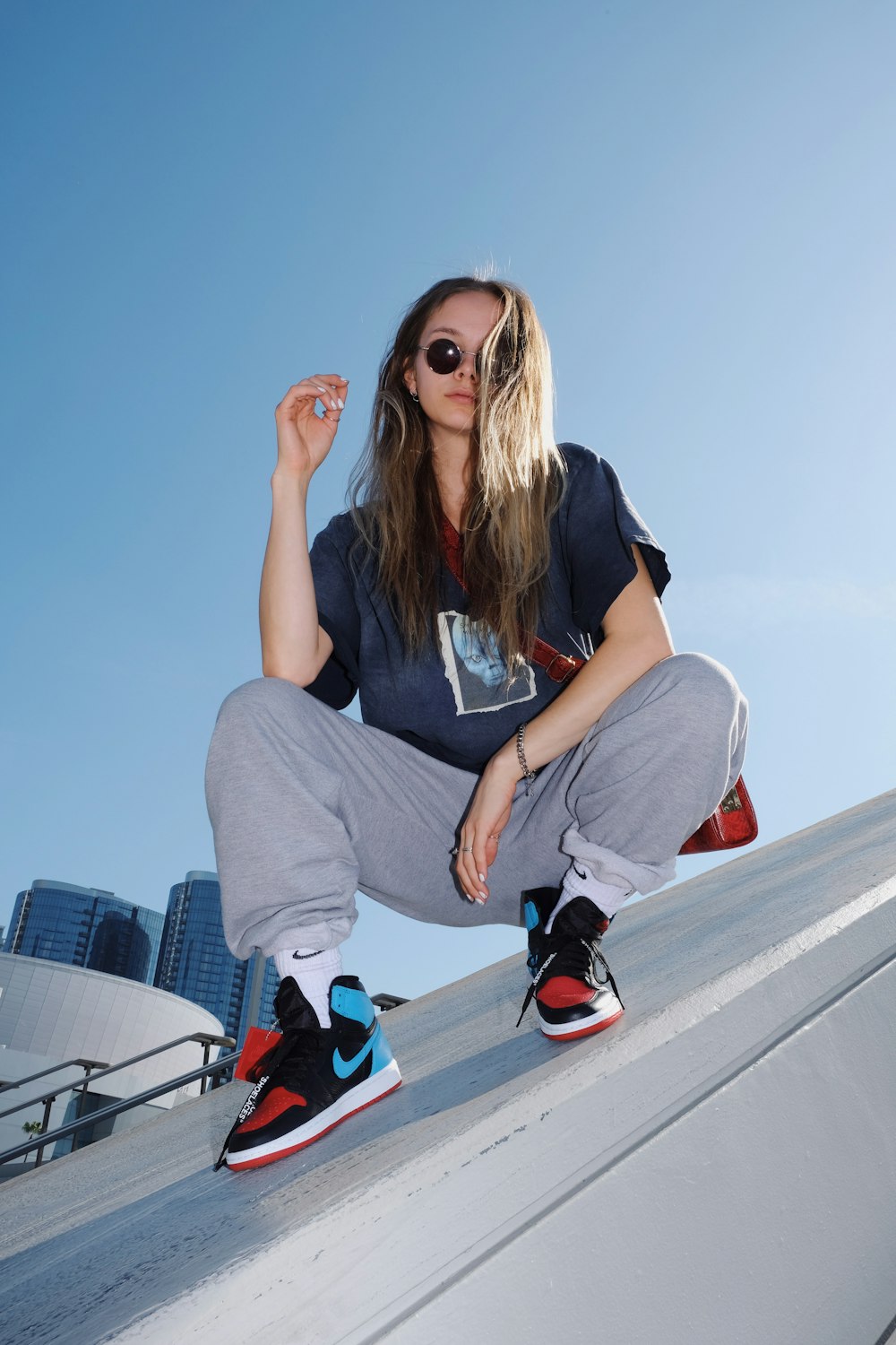 woman in black t-shirt and gray pants sitting on white metal railings during daytime