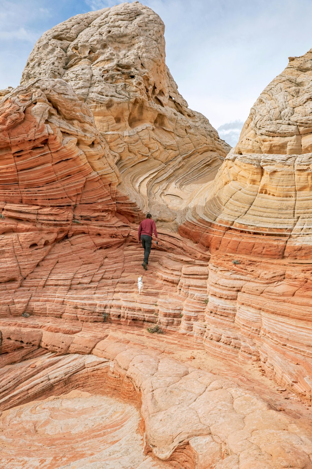 man in black jacket and blue denim jeans walking on brown rock formation during daytime