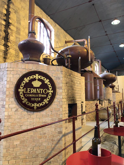 Close-up of a handcrafted copper alembic still gleaming under warm light in a rustic distillery setting.