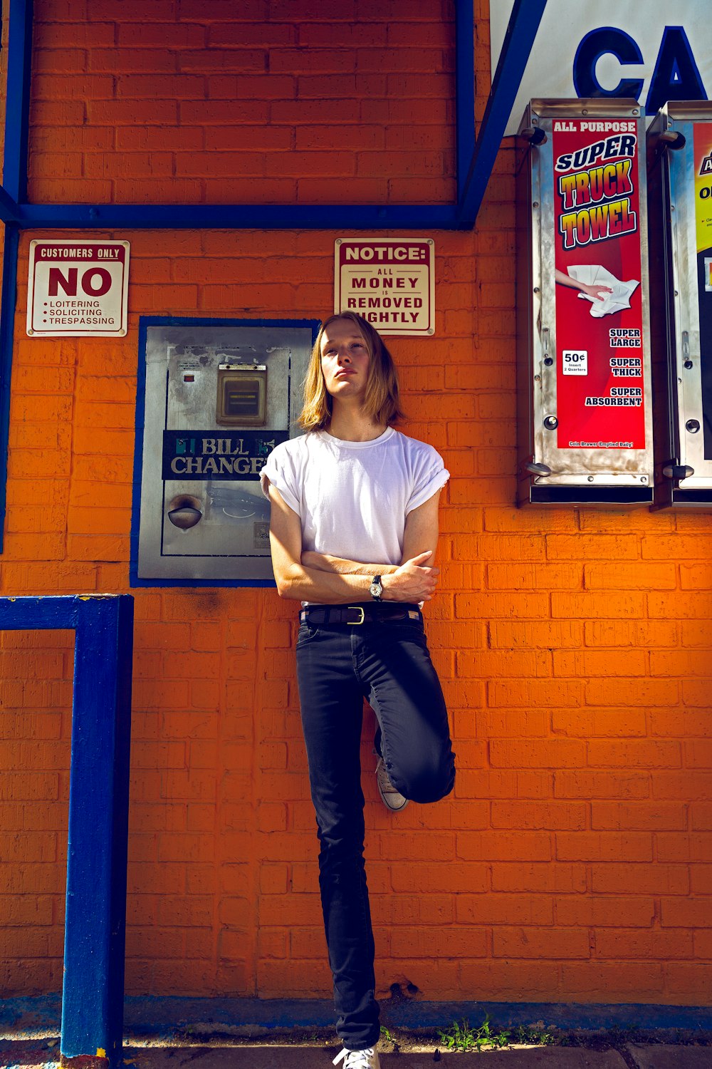 woman in white t-shirt and blue denim jeans standing near red and blue door