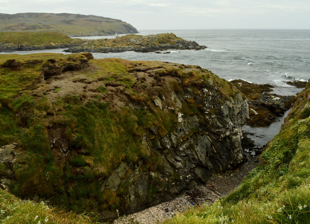 green and brown rock formation near body of water during daytime